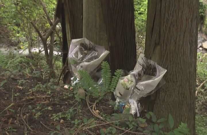 女性の遺体が発見された場所に花束が供えられている。